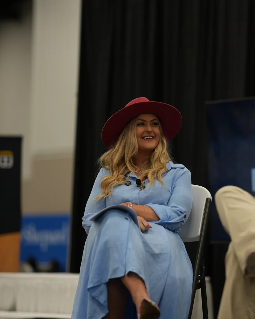 Stefanie Couch smiling with a guest during a panel conversation on stage