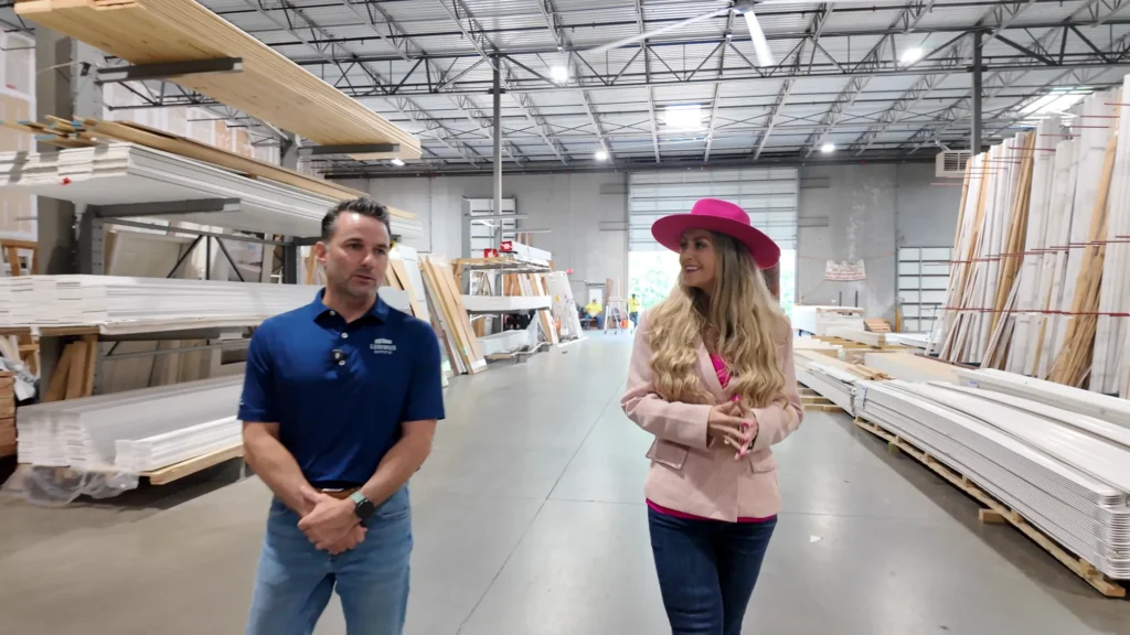 Stefanie Couch with a guest among the door and trim racks in a warehouse