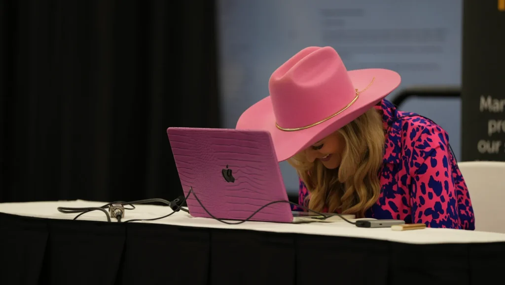 Stefanie Couch running a live AI demo at her pink laptop on stage at Do it Best Fall Market 2025