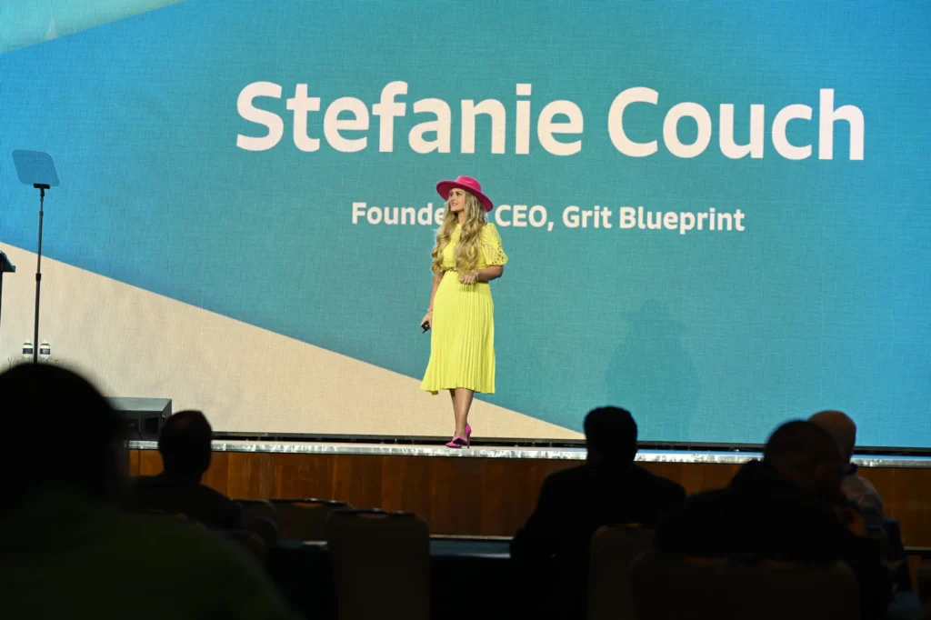 Stefanie Couch on the Employee Owned 2025 stage beneath a giant screen showing her name and title