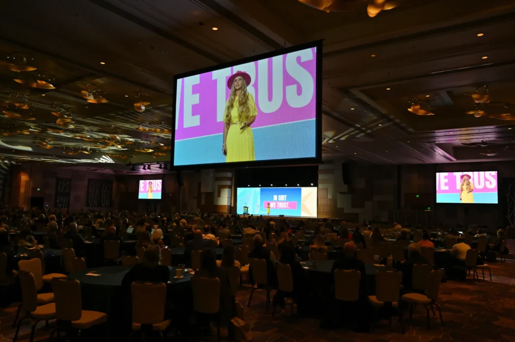 A packed ballroom at Employee Owned 2025 with Stefanie Couch on the big screens