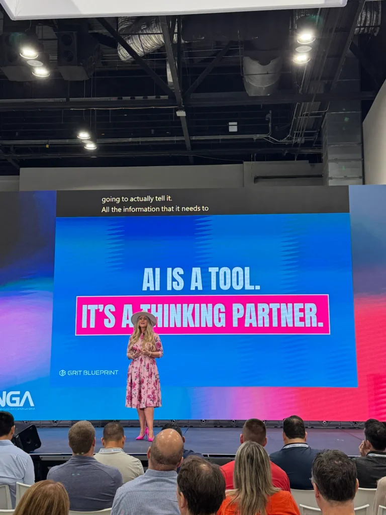 Stefanie Couch on the GlassBuild America 2025 main stage beneath a slide that reads AI Is a Tool. It’s a Thinking Partner.