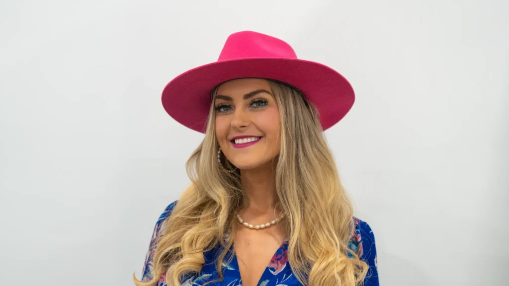 Stefanie Couch smiling in a pink hat and pearls at NHS Concept to Commerce 2026