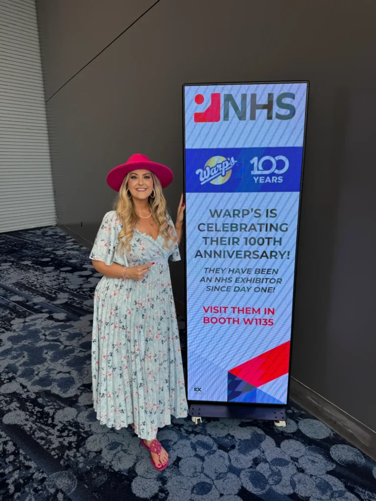Stefanie Couch beside the National Hardware Show 100th anniversary banner