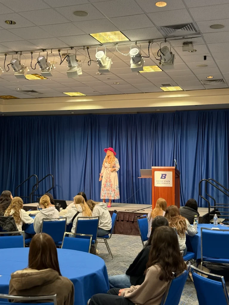 Stefanie Couch speaking at the podium to a room of women at Young Women and Leadership