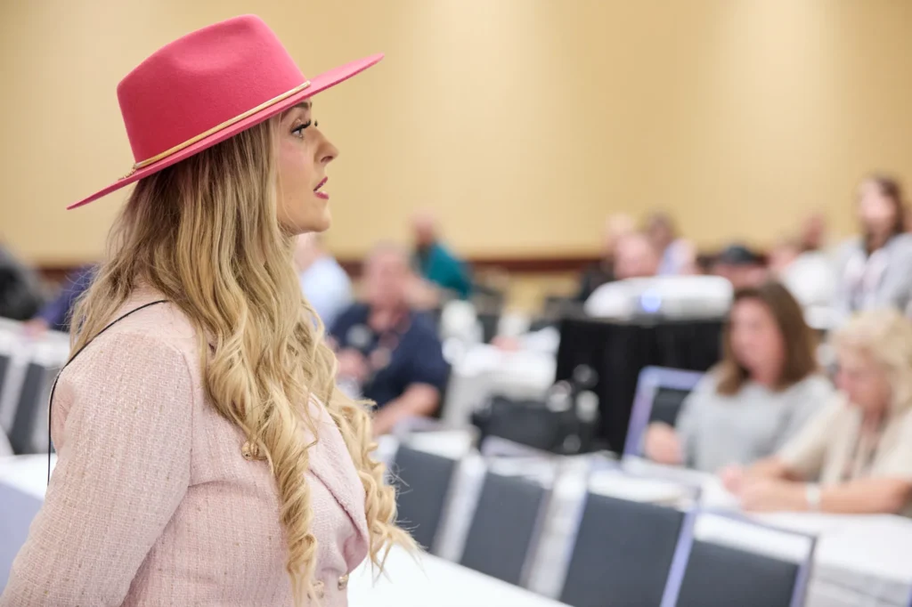 Stefanie Couch in profile during her AI session at Do it Best Fall Market 2026, attendees at tables behind her
