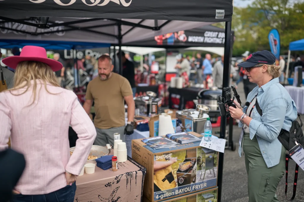 A Grit Blueprint camera operator films at the Bayou Classic booth as Stefanie Couch talks with a vendor