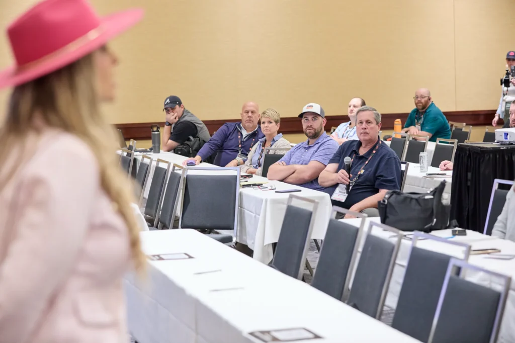 Attendees at their tables listening during Stefanie Couch’s AI session at a trade show