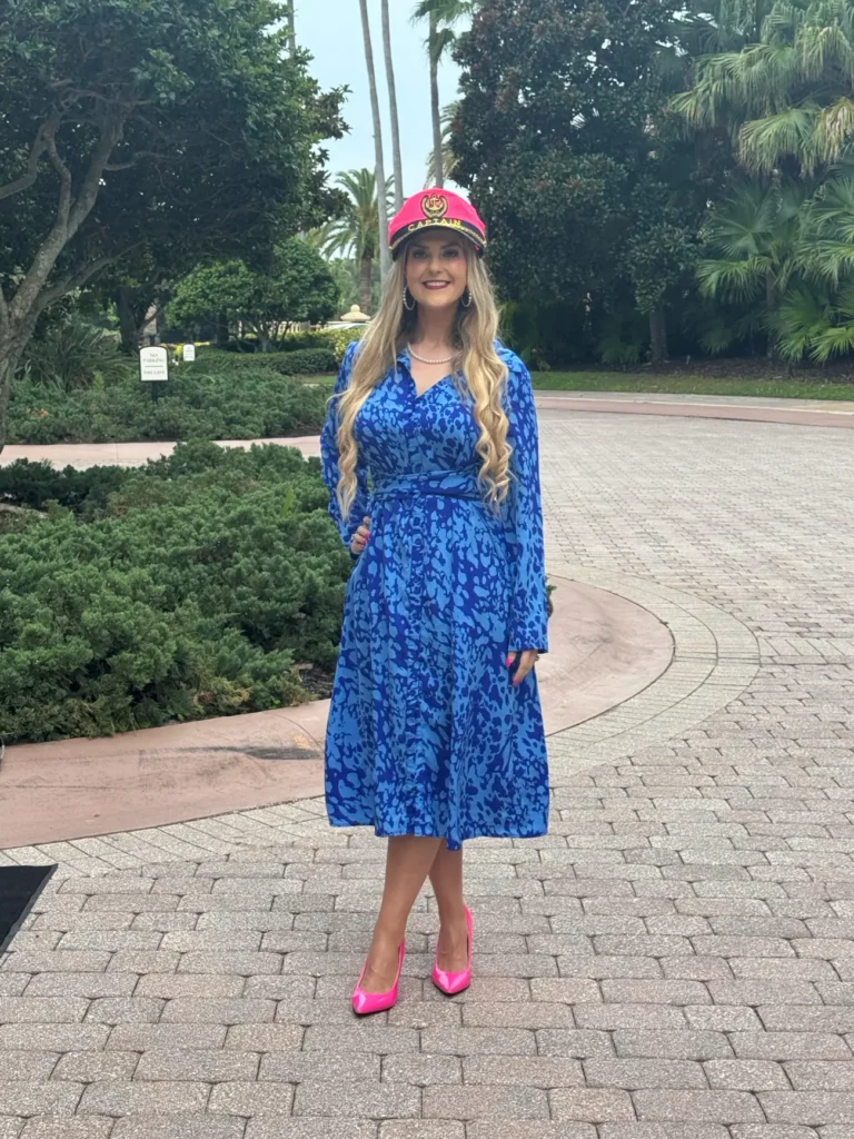 Stefanie Couch smiling in a pink captain’s hat and a blue print dress among the palm trees at the Independent Home Improvement Conference 2026