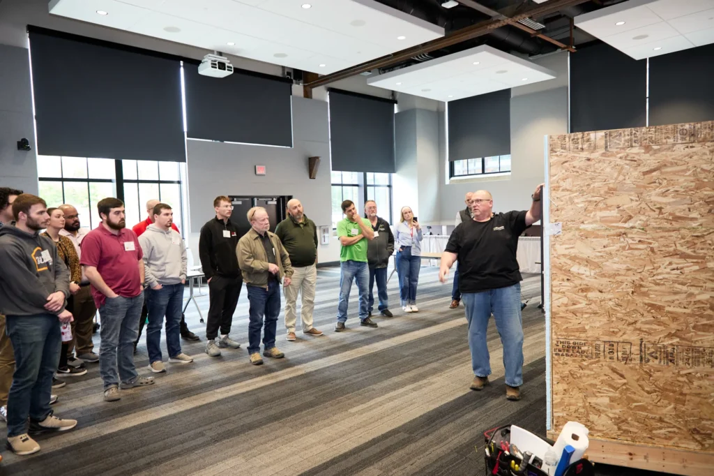 Attendees gather around an OSB wall demo at the Do it Best LBM Millwork Academy