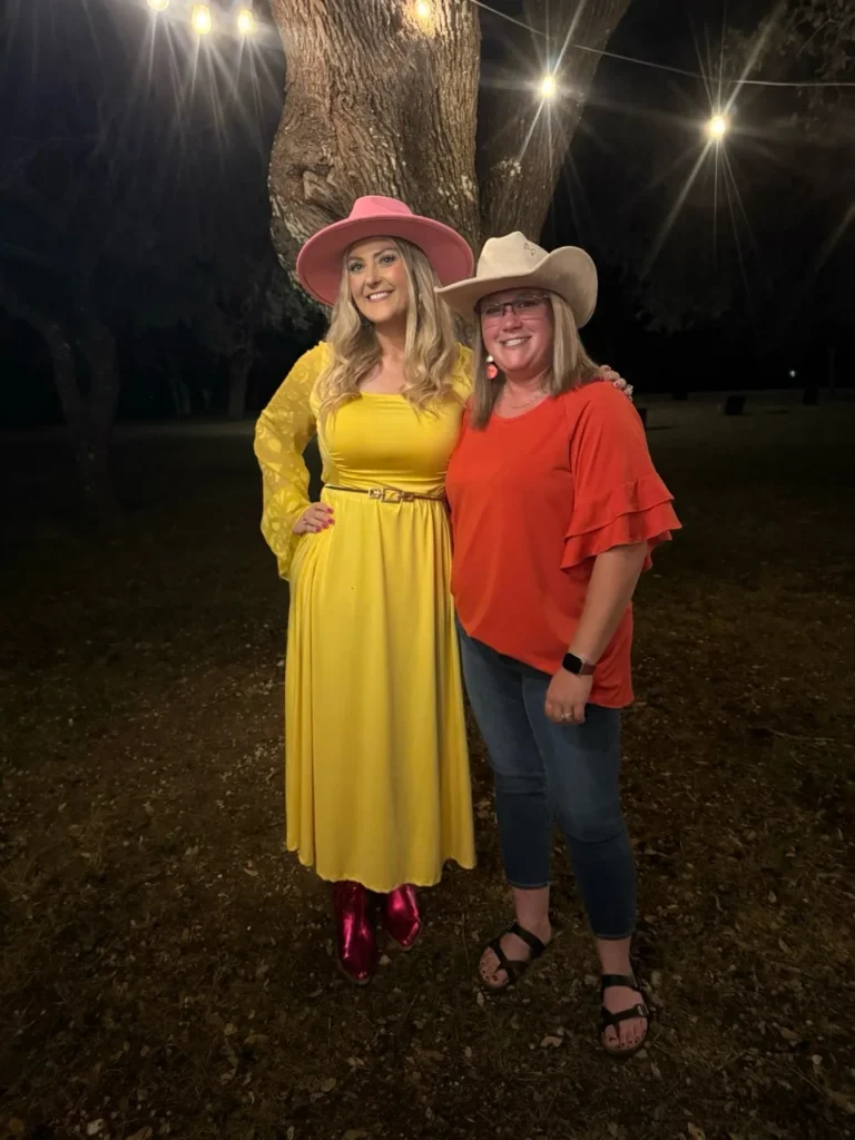 Stefanie Couch with an attendee in a cowboy hat under string lights at the Nation’s Best Women’s Leadership Retreat