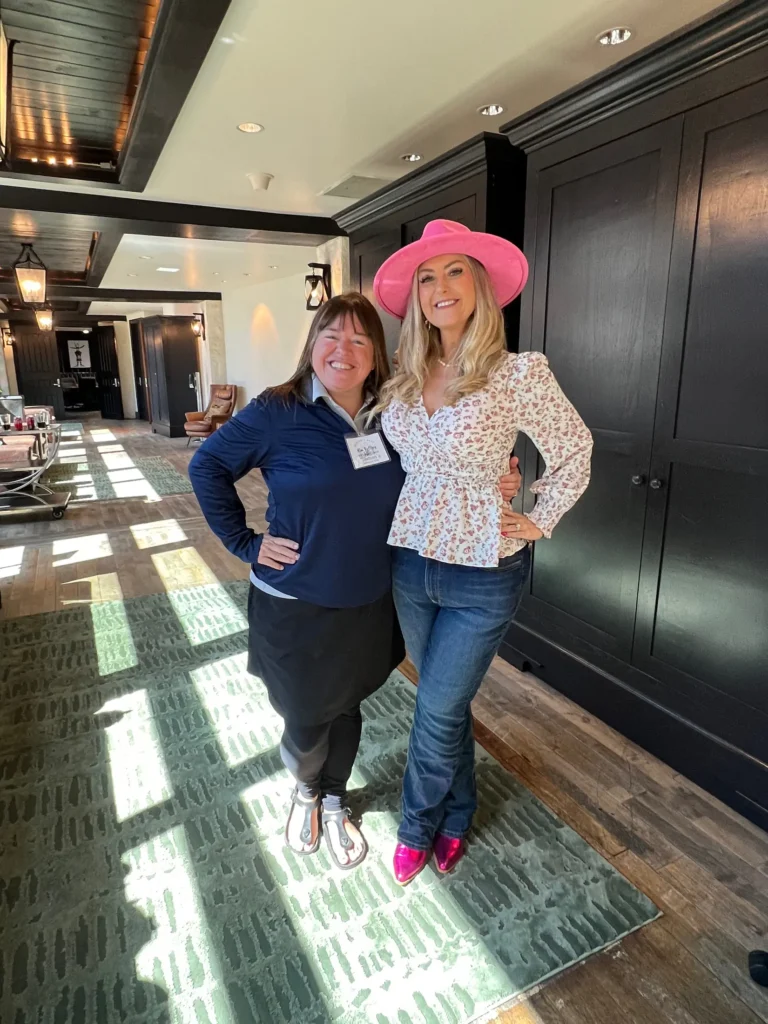 Stefanie Couch with an attendee in a sunlit hallway at Rough Creek Lodge