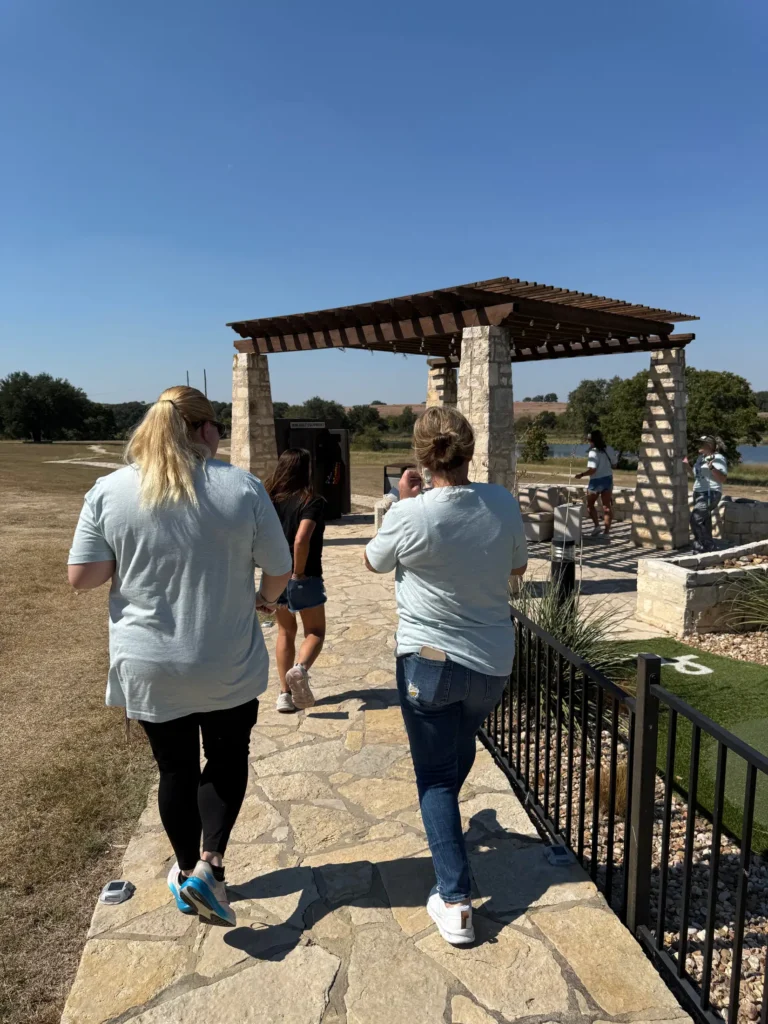 Retreat attendees walk toward a stone pergola by the lake at Rough Creek Lodge