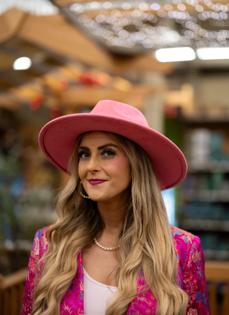 Stefanie Couch smiling in a pink hat, pearls and a pink floral blazer