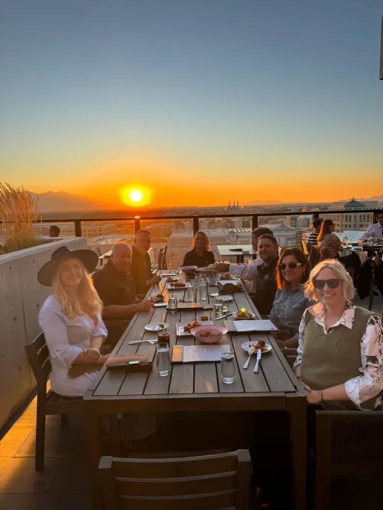 Guests at a Sierra Pacific Windows customer dinner, seated at a long table on a rooftop at sunset