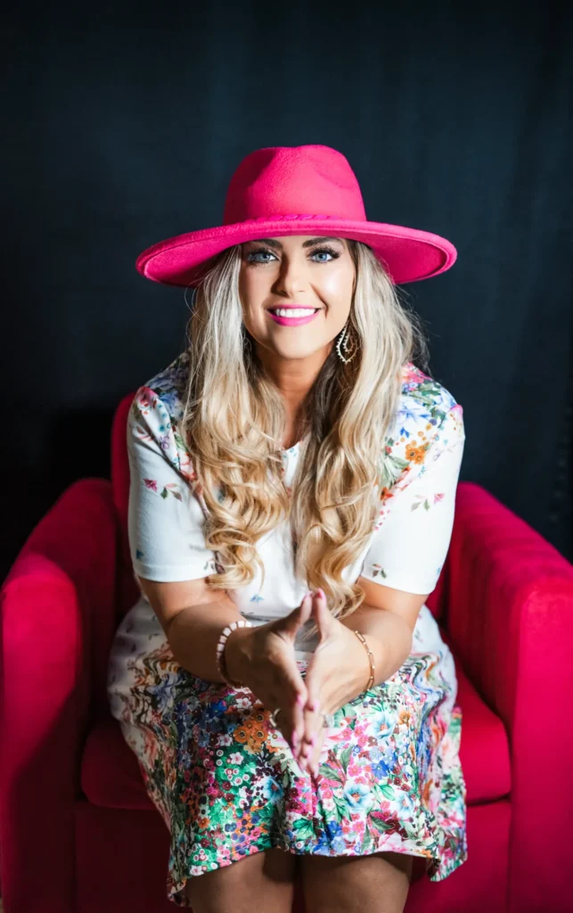 Stefanie Couch leaning forward with a warm smile, seated in a pink armchair